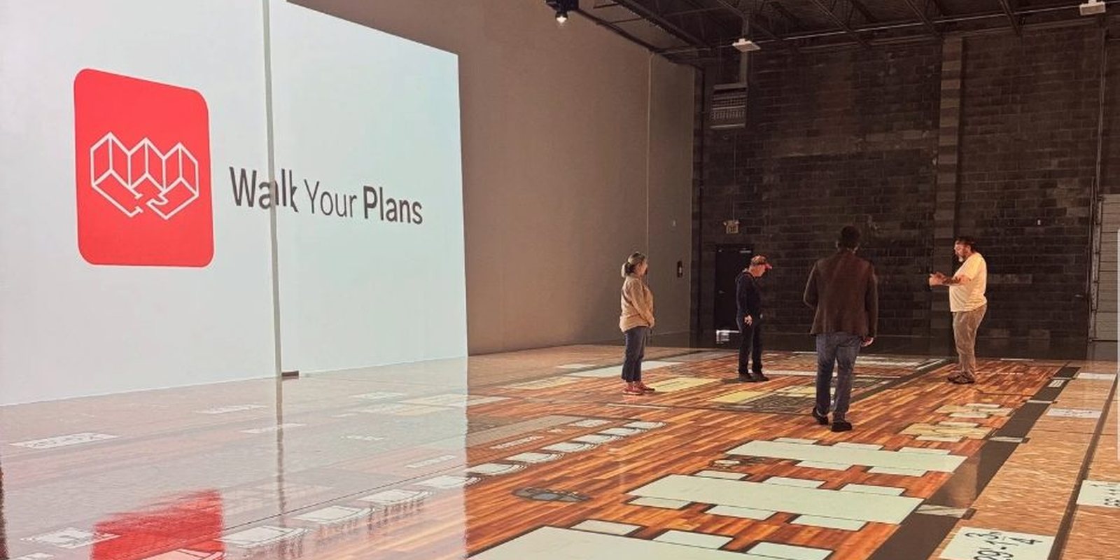 A team walking a large layout projected across the studio floor