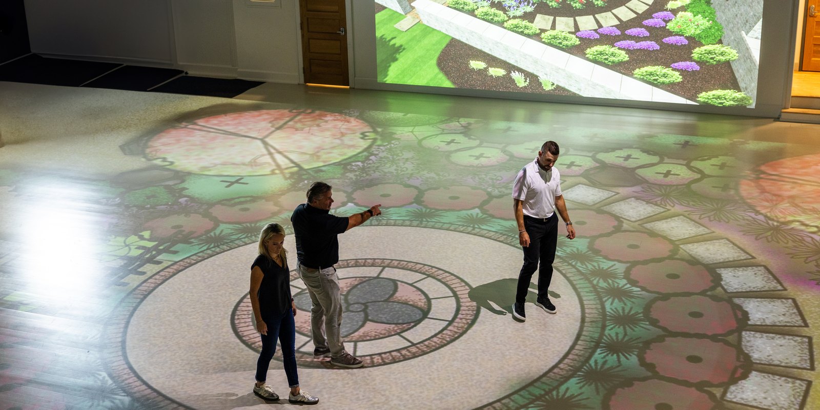 A landscaped garden environment projected across the studio floor with guests standing on it